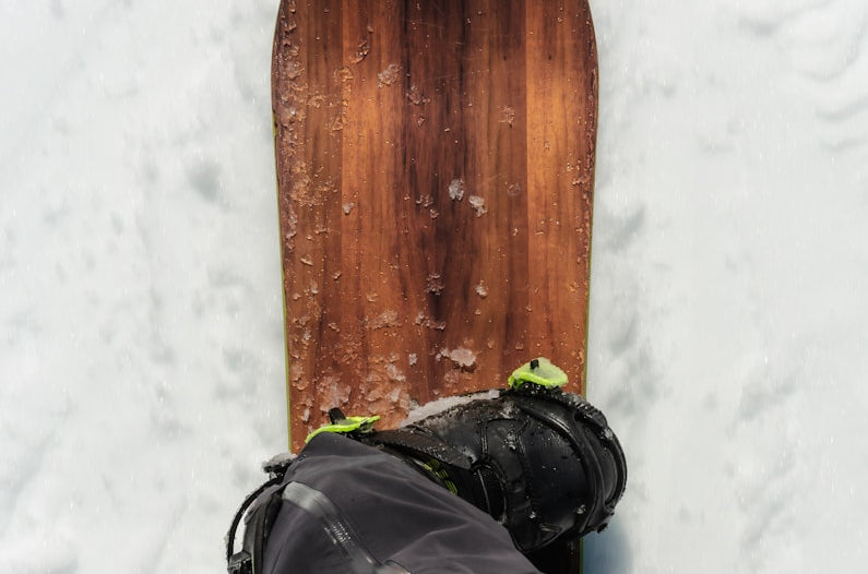 a person's feet in the snow next to a snowboard
