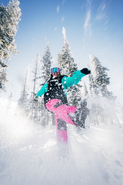 person in blue jacket and pink pants riding on snowboard during daytime